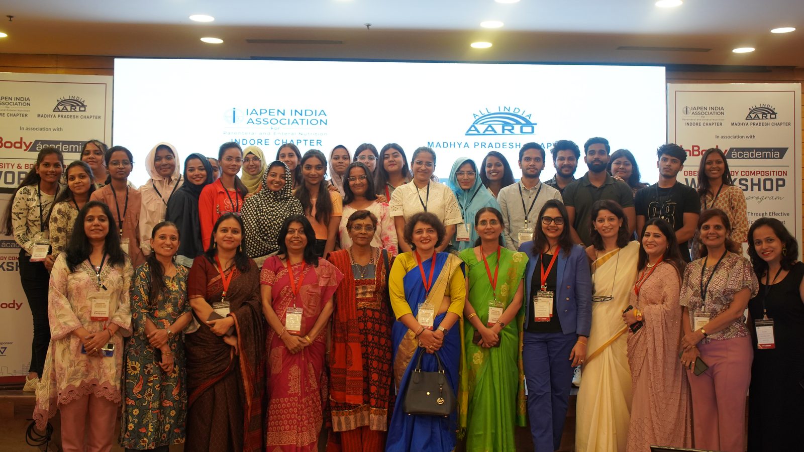 Delegates and organisers in front of the IAPEN India and AARD backdrop at Ácademia Indore 2024.