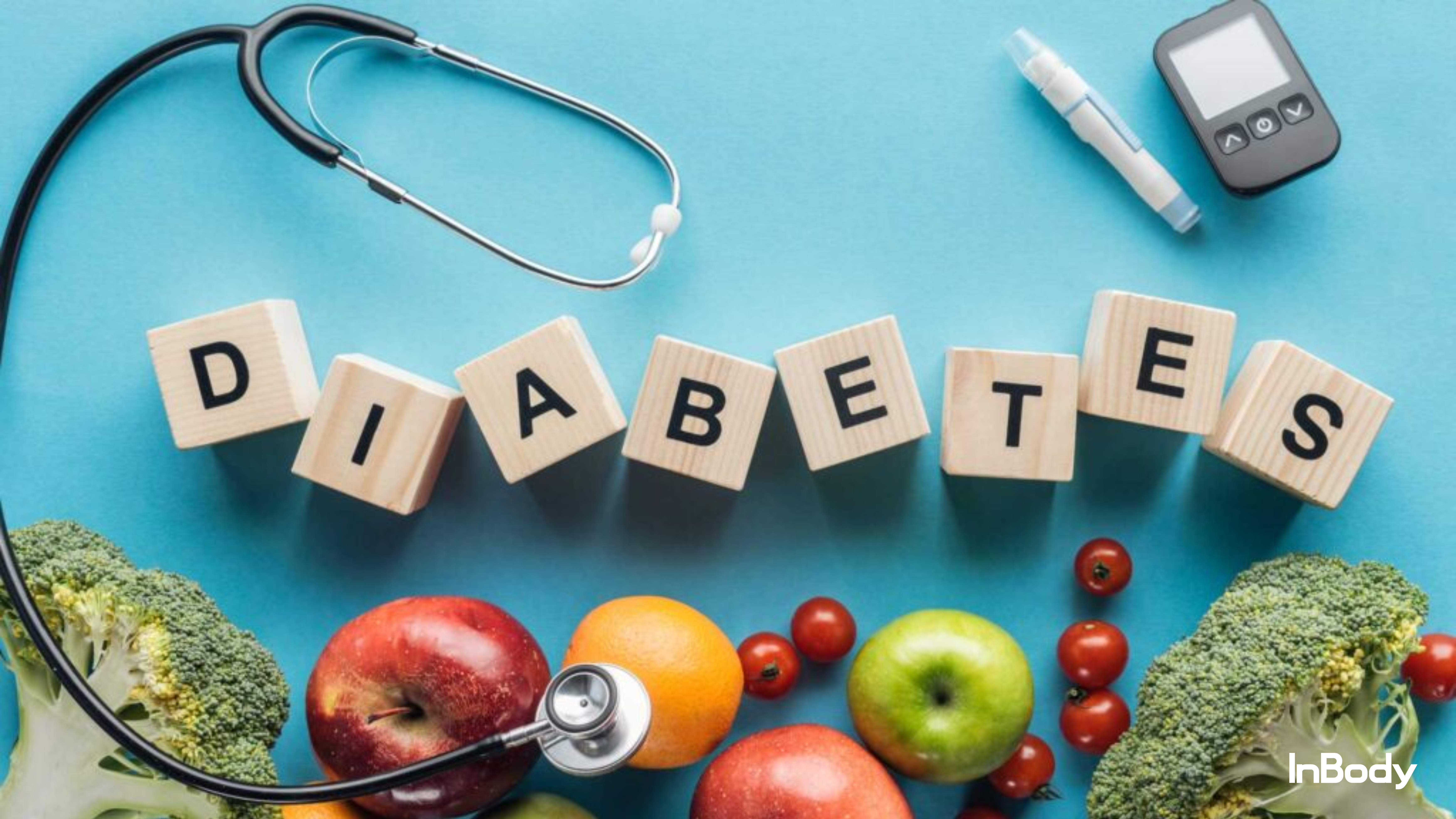 Wooden blocks spelling "DIABETES" surrounded by healthy fruits, vegetables, a stethoscope, and a glucose monitor on a blue background.